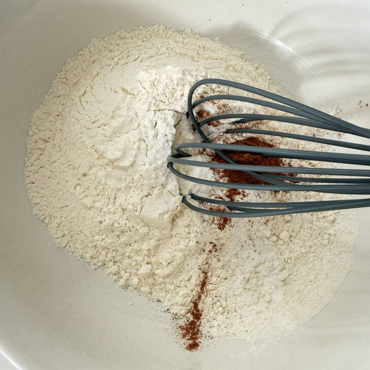 Dry ingredients in a mixing bowl with a whisk.