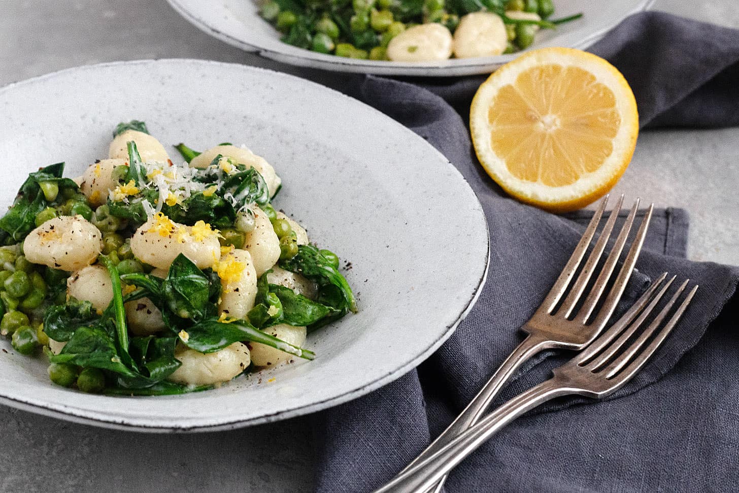 creamy lemon gnocchi with peas and spinach in bowls