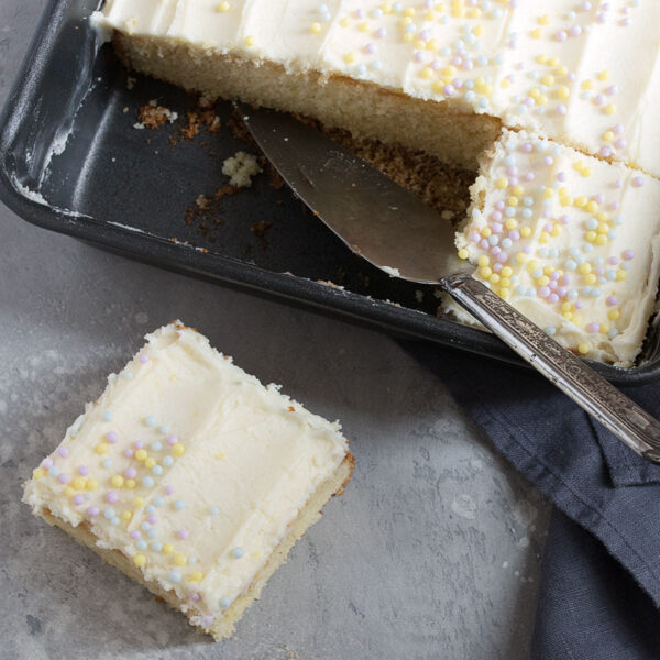 lemon sheet cake in pan with a slice out
