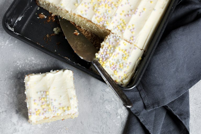 lemon sheet cake in pan with one slice out