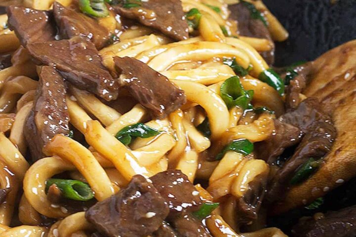 mongolian beef and udon noodles in cast iron wok