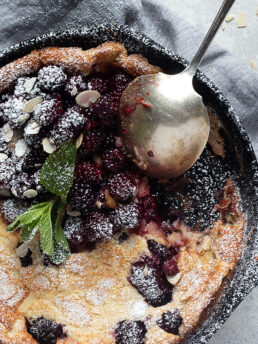 blackberry Dutch baby in cast iron skillet with spoon