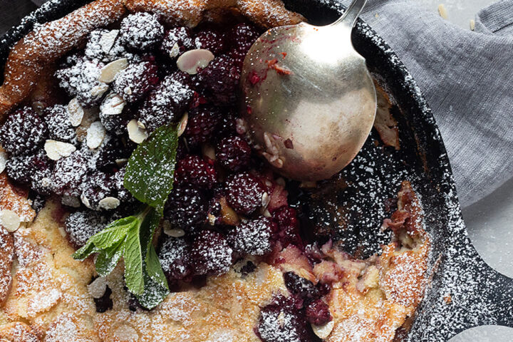 blackberry Dutch baby in cast iron skillet with spoon