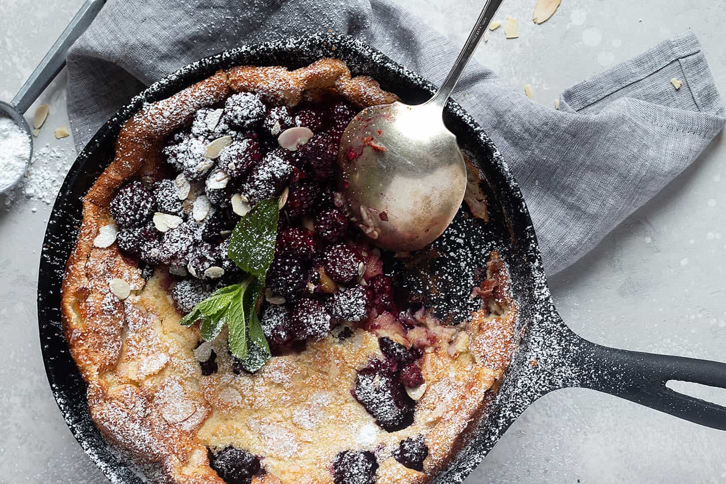 blackberry Dutch baby in cast iron skillet with spoon