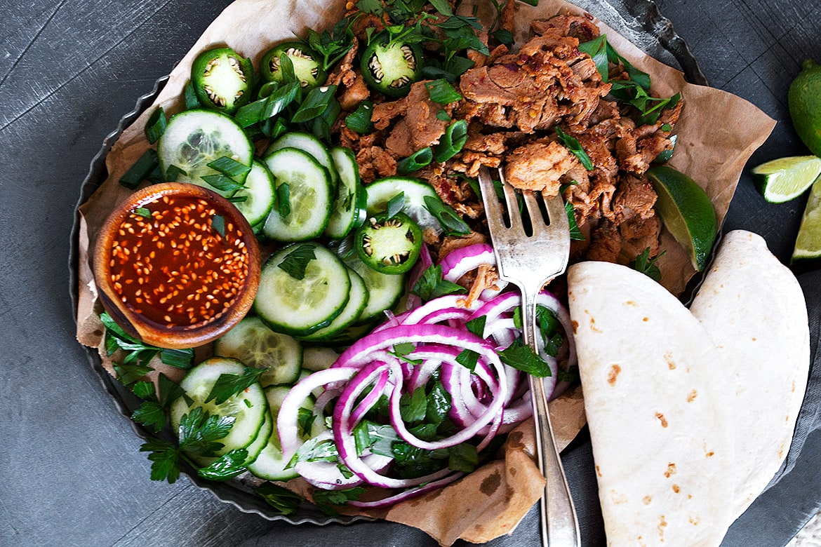 spicy pork in pan with toppings and tortillas