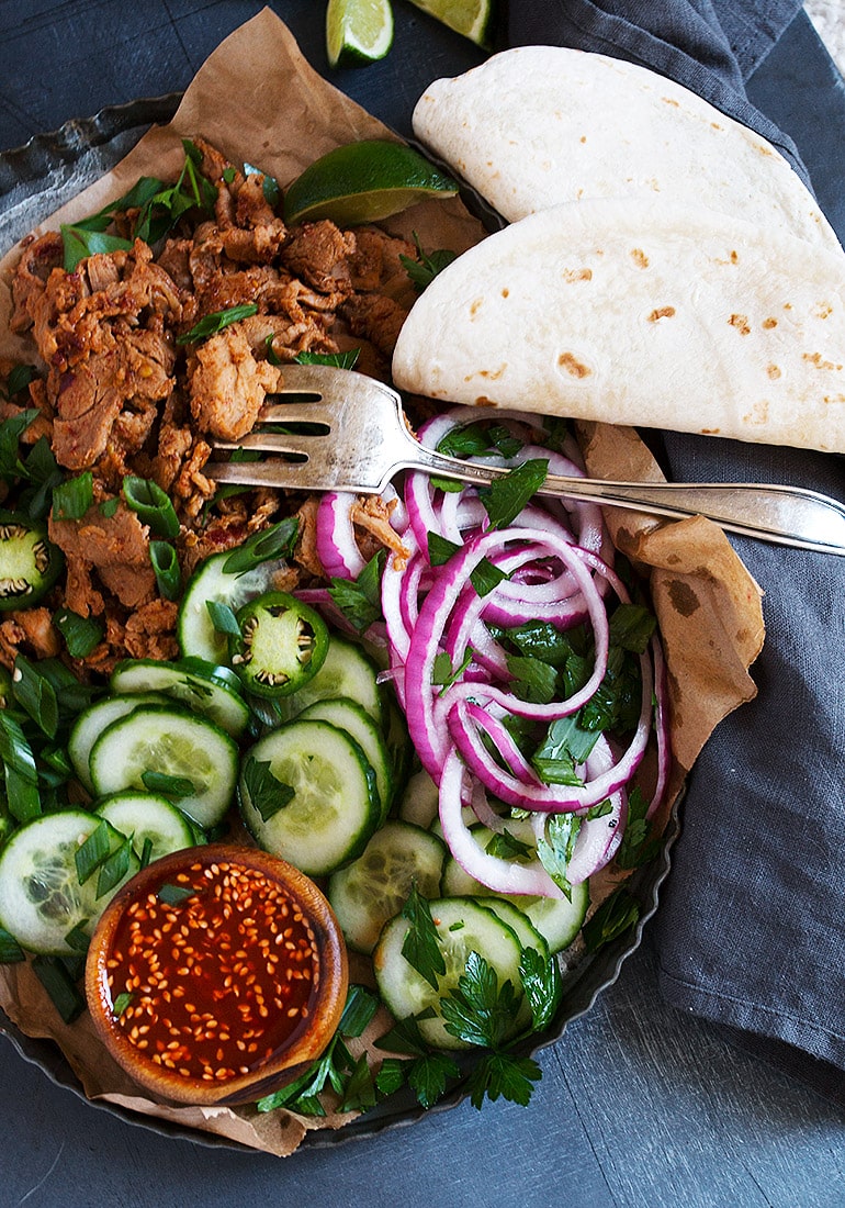 spicy pork in pan with toppings and tortillas