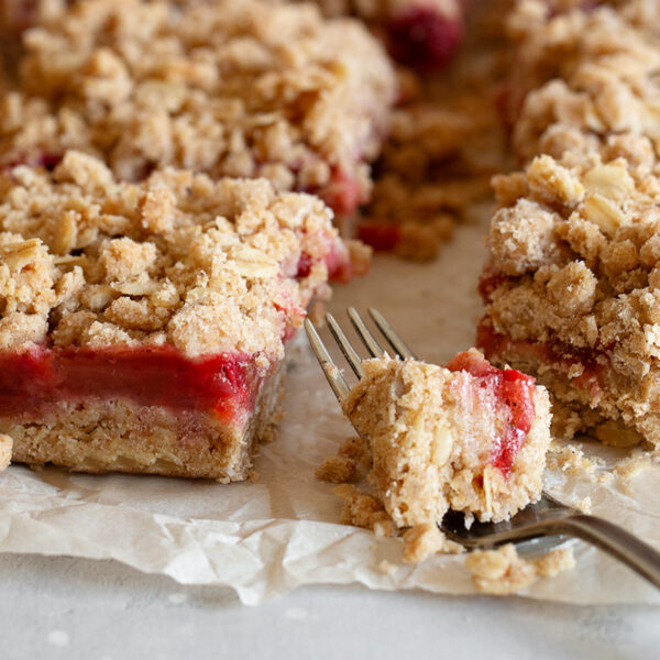 Strawberry rhubarb crumb squares cut on parchment paper.