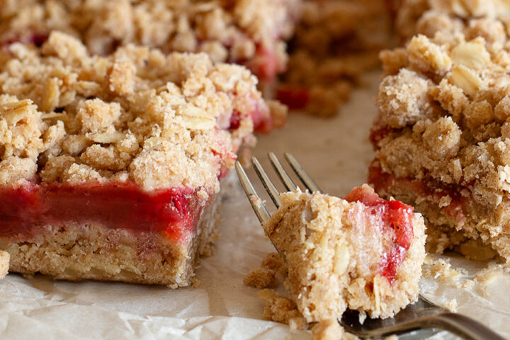 Strawberry rhubarb crumb squares cut on parchment paper.