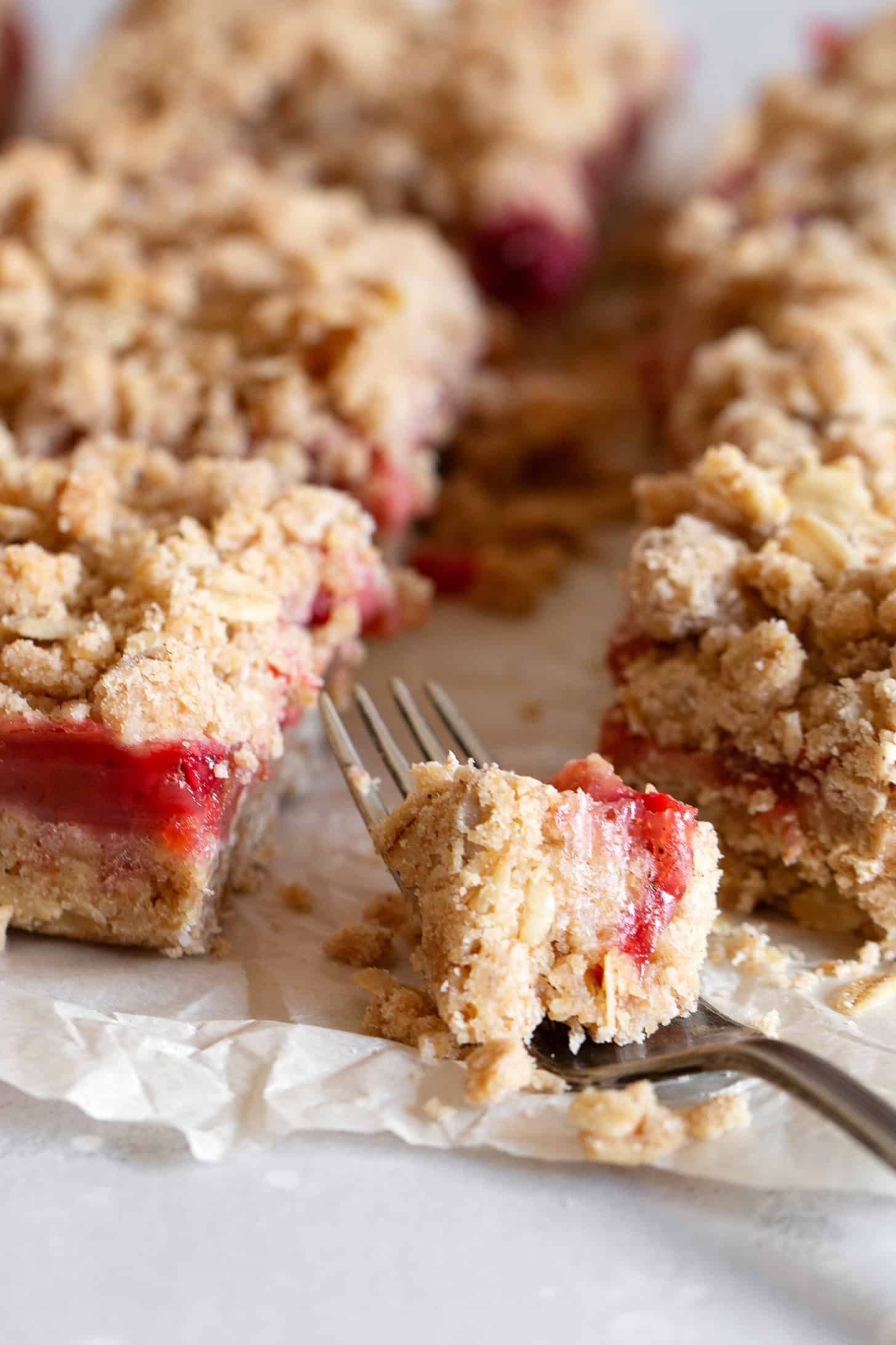 Strawberry rhubarb crumb squares cut on parchment paper.