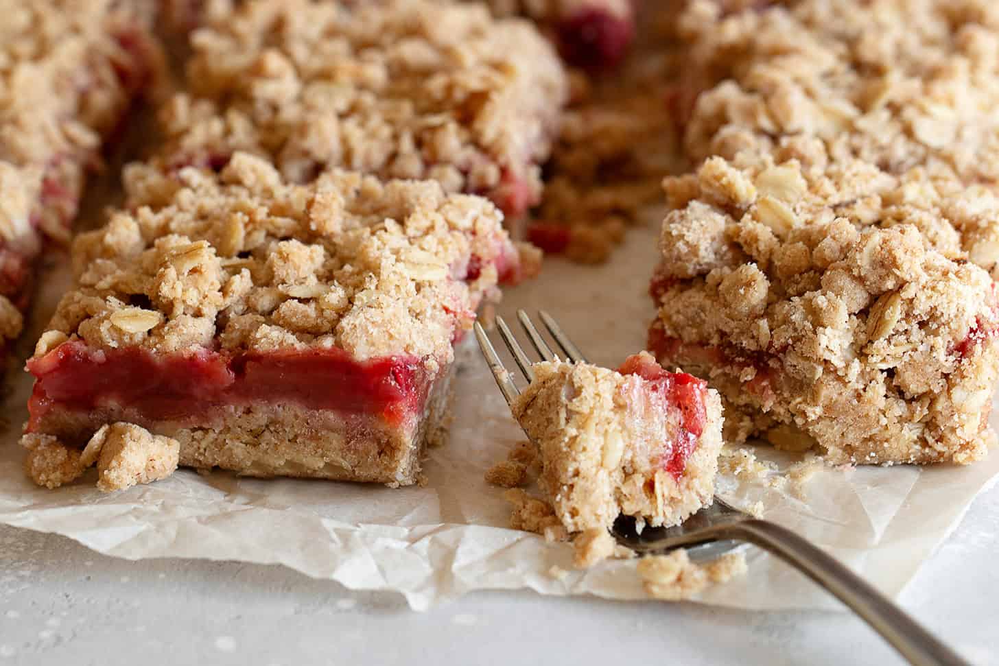 Strawberry rhubarb crumb squares cut on parchment paper.