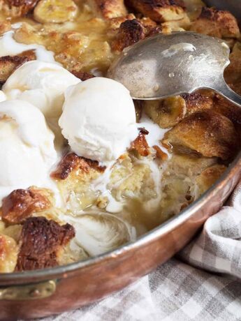 bananas foster bread pudding in copper baking pan with ice cream