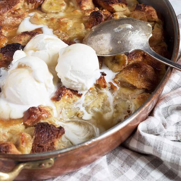 bananas foster bread pudding in copper baking pan with ice cream