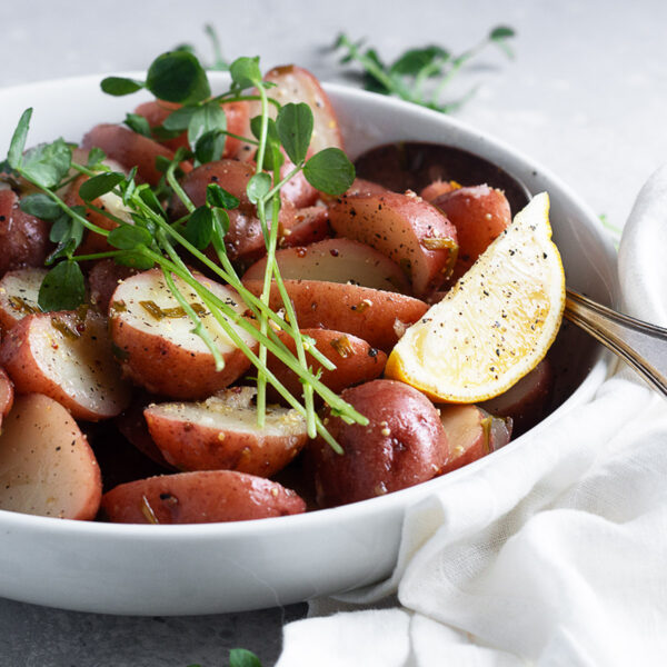Lemon potato salad in a serving bowl with lemon wedges.