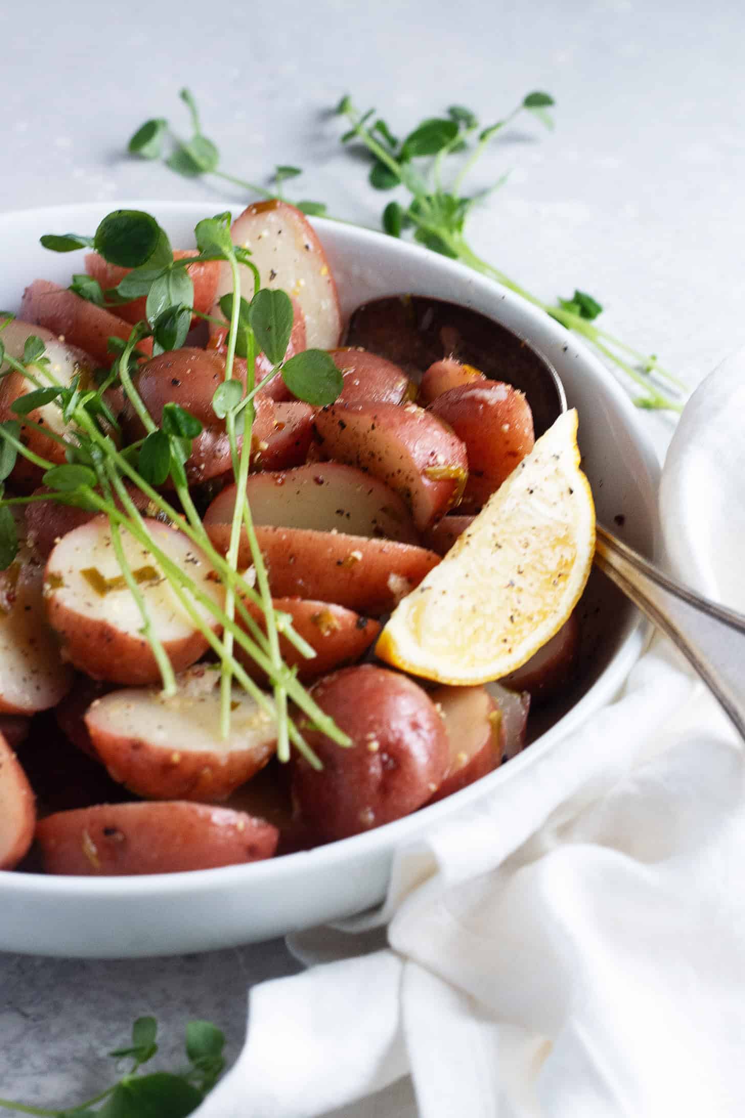 Lemon potato salad in a serving bowl with lemon wedges.