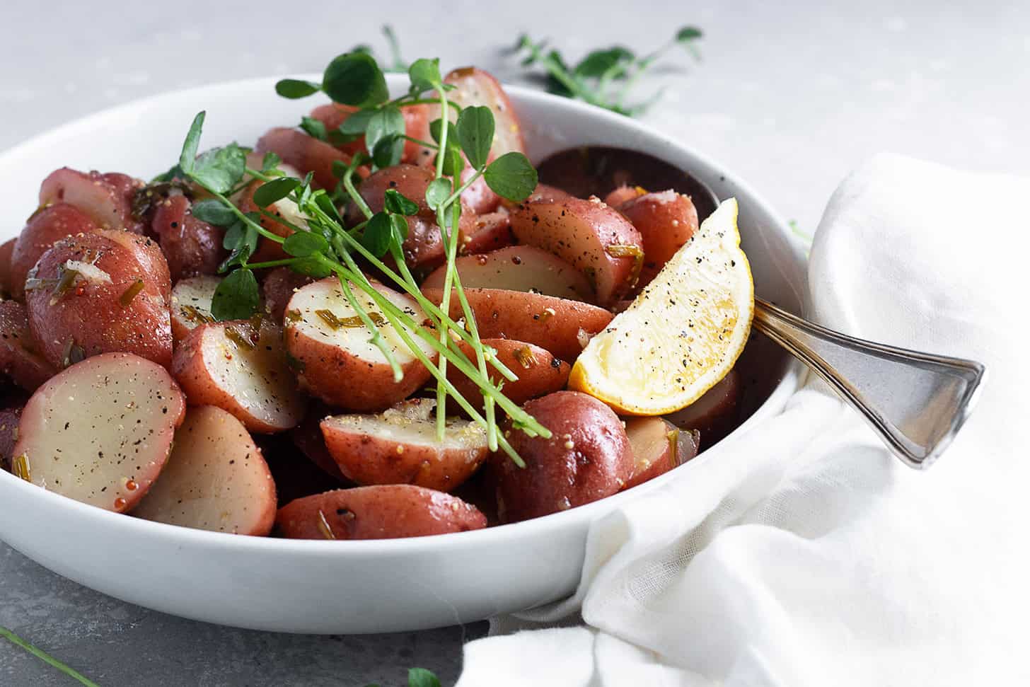 Lemon potato salad in a serving bowl with lemon wedges.
