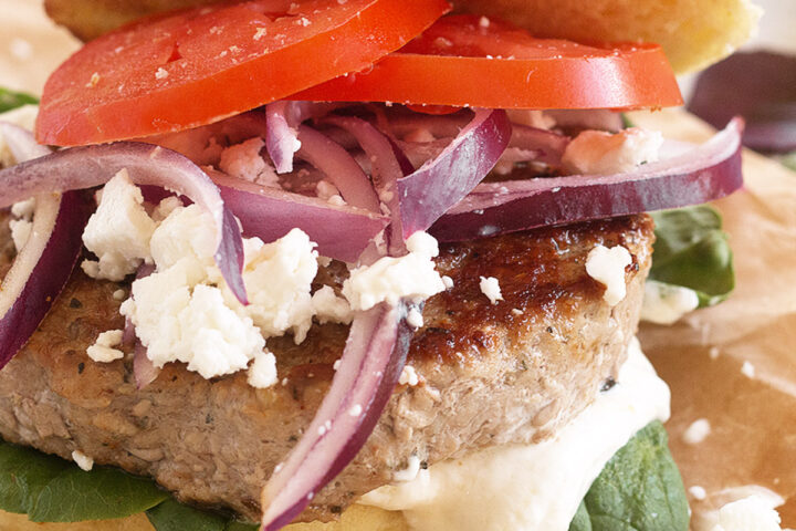 Pork souvlaki burger on parchment paper.