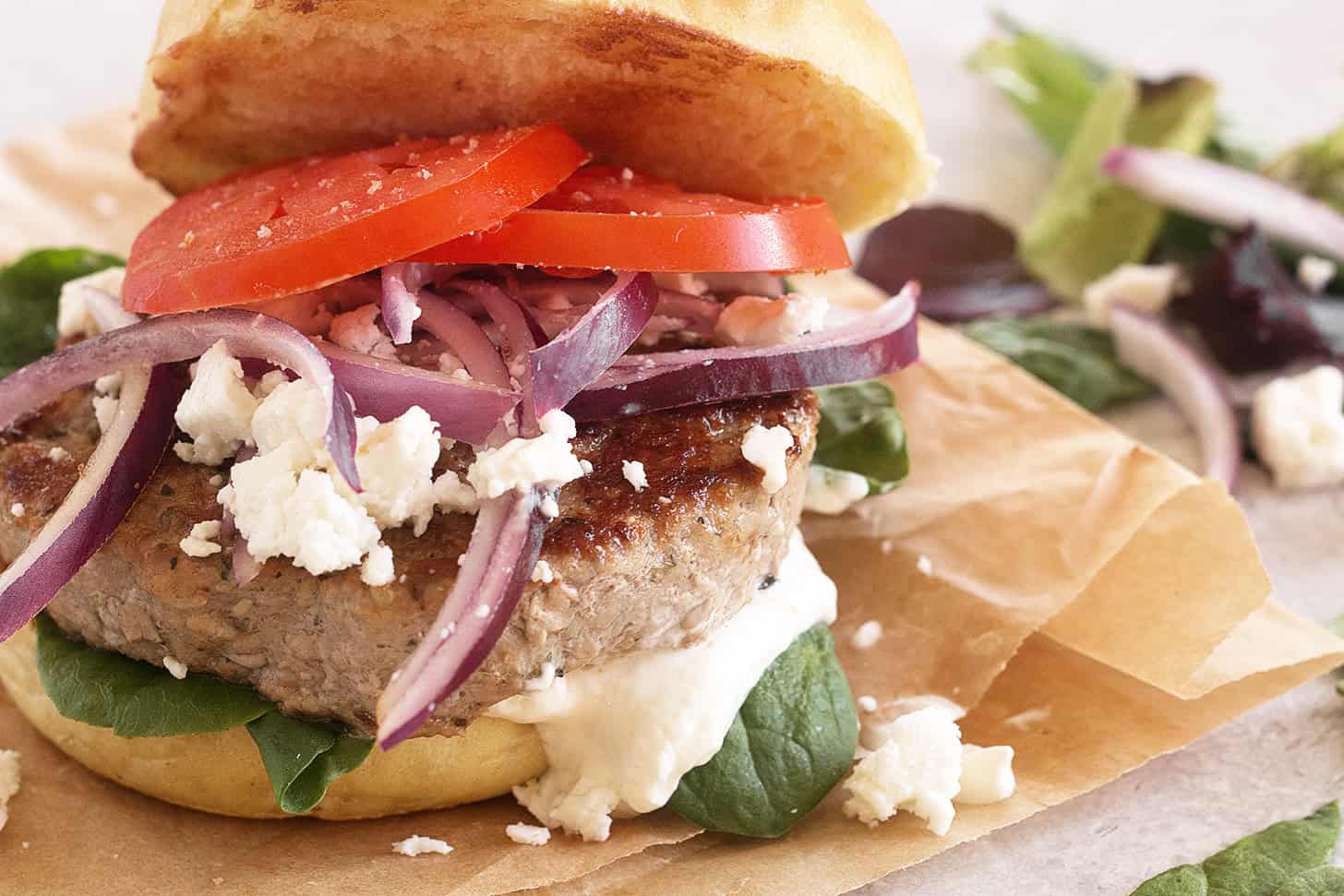 Pork souvlaki burger on parchment paper.
