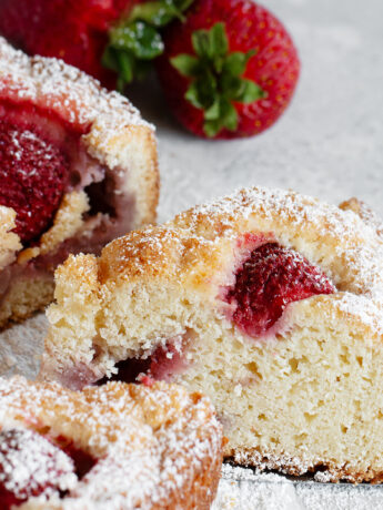 Rustic strawberry cake sliced on parchment paper.