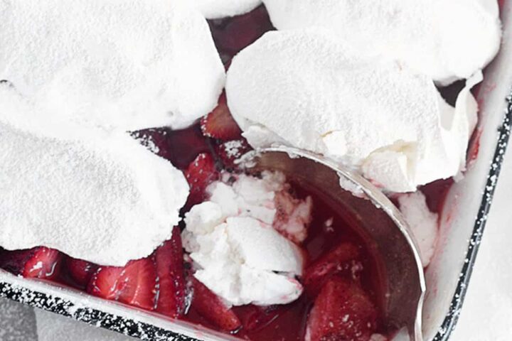 roasted strawberries with meringue topping in baking dish with spoon