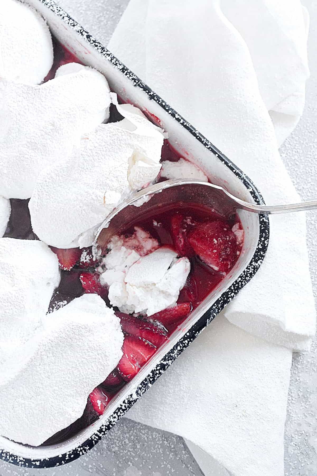 roasted strawberries with meringue topping in baking dish with spoon