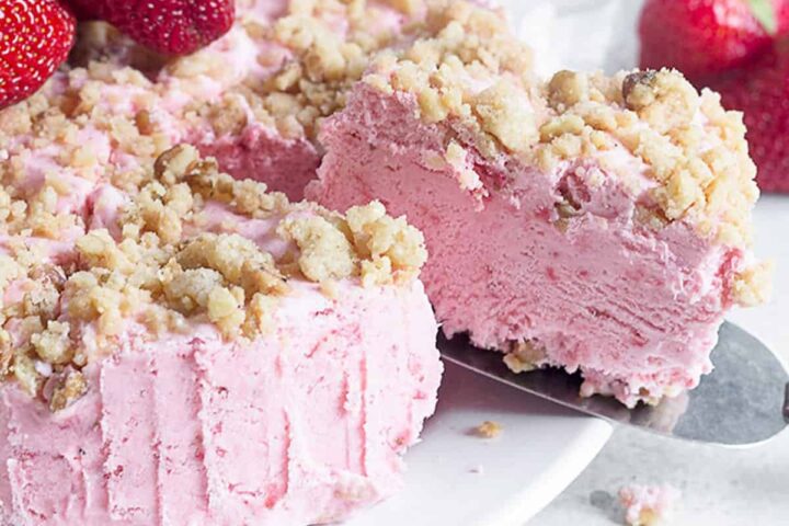 frozen strawberry cake sliced on platter with fresh strawberries