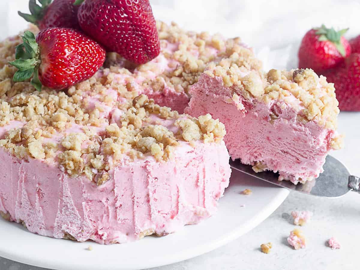 frozen strawberry cake sliced on platter with fresh strawberries