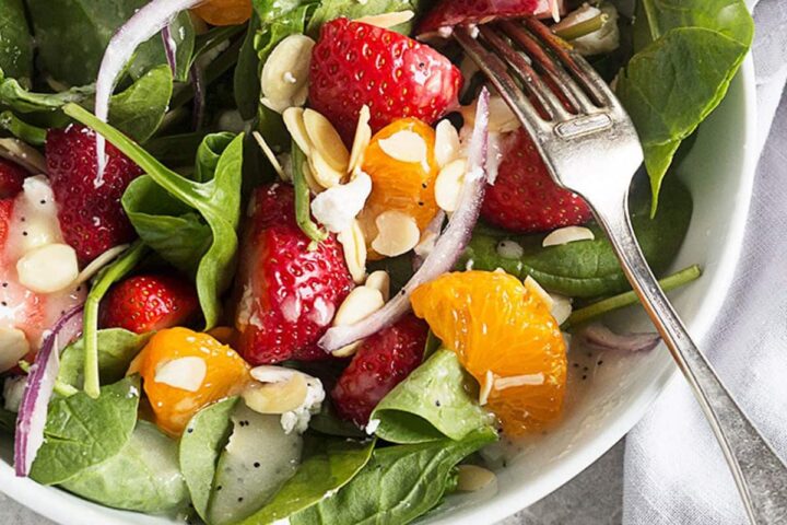 spinach strawberry salad in white bowl with fork