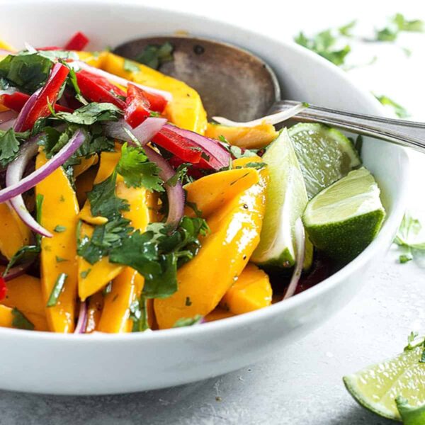 mango salad in white bowl with spoon