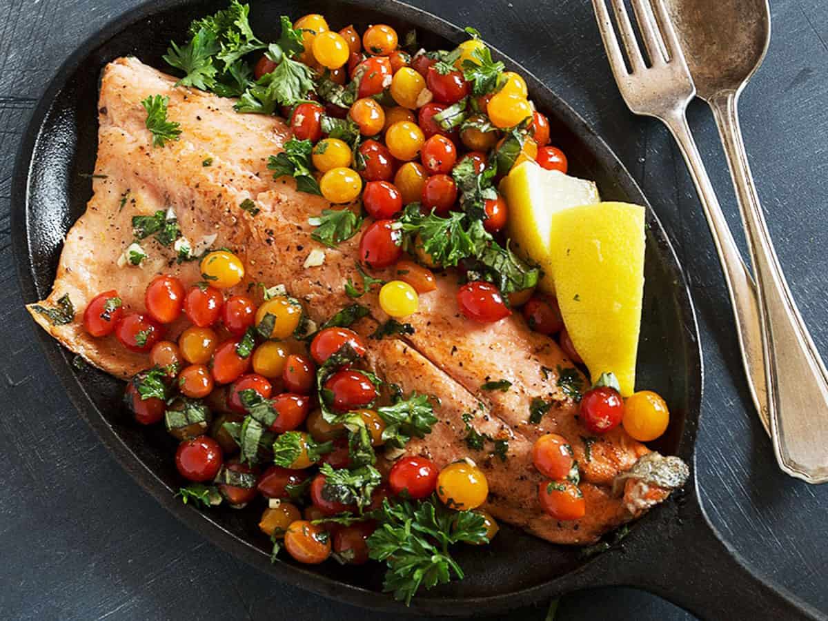 rainbow trout with mini cherry tomatoes in skillet
