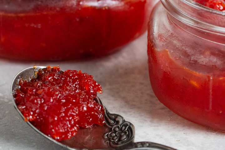 red pepper jam with jars and jam on spoon