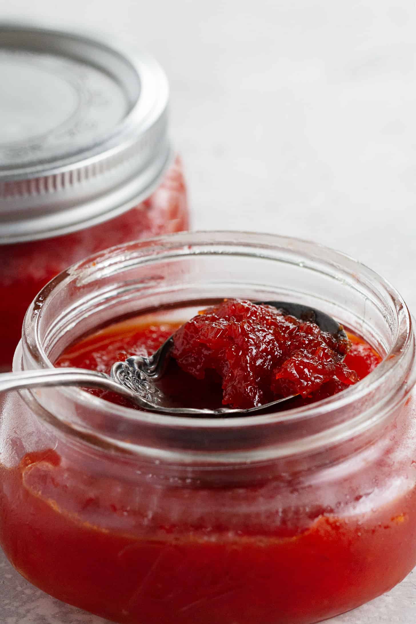 red pepper jam with jars and jam on spoon