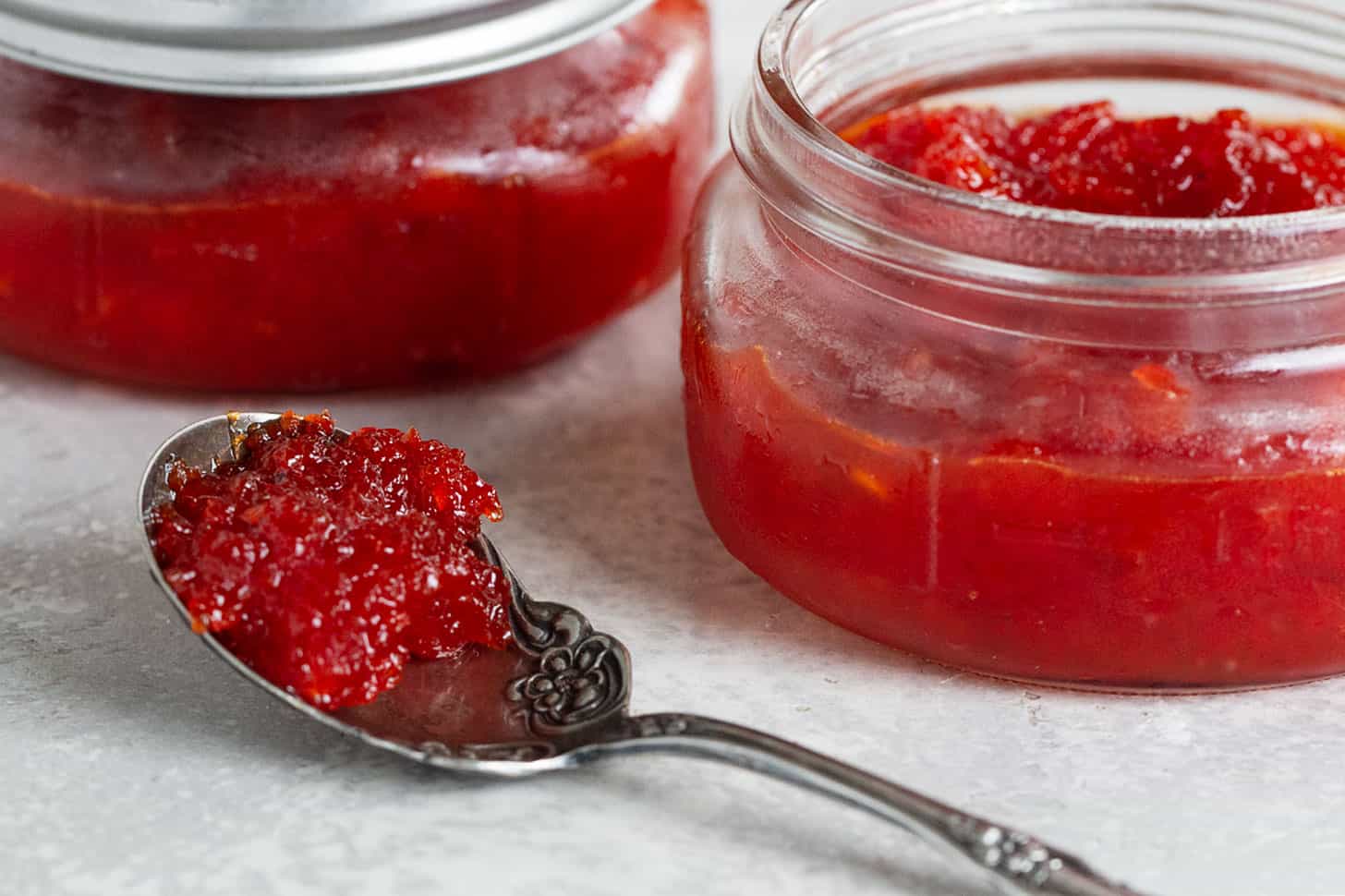 red pepper jam with jars and jam on spoon