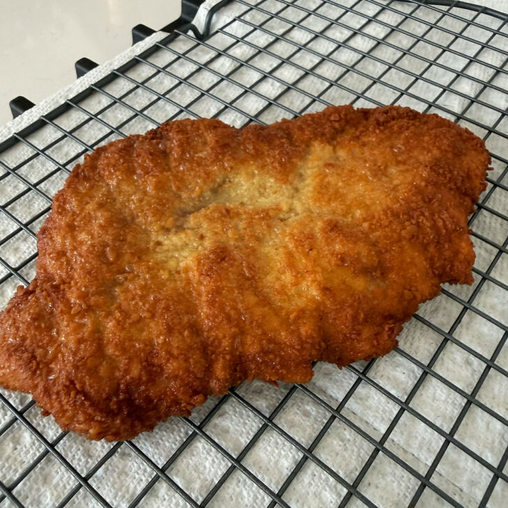 Freshly fried pork schnitzel on a wire rack.