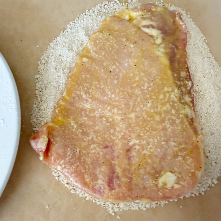 Coating the egg-dipped pork into breadcrumbs.