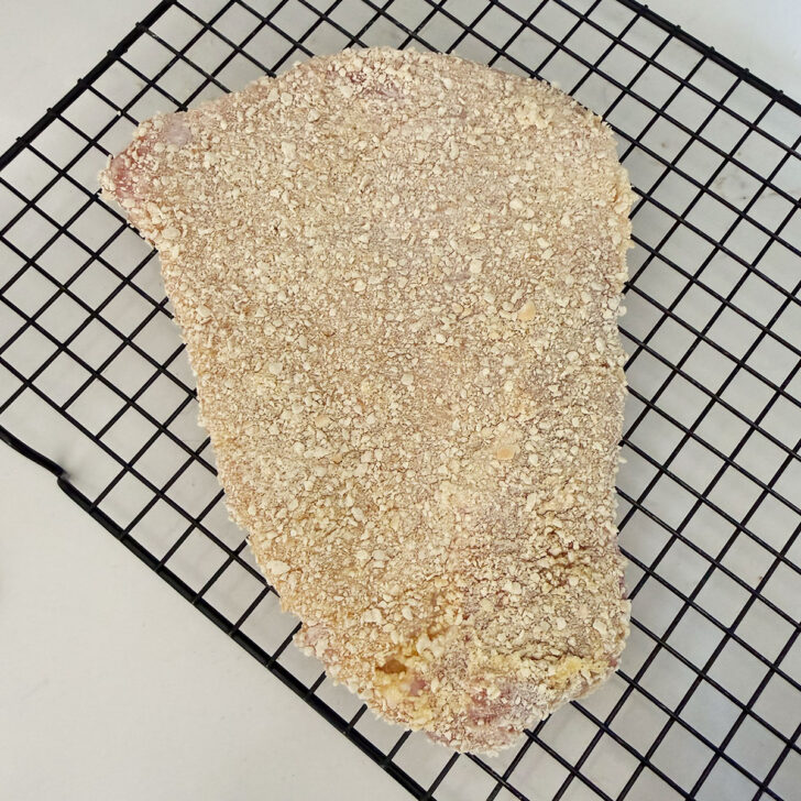 Breaded pork for schnitzel on a wire rack.