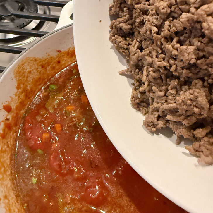 Returning the meat to the pot with the tomato sauce.
