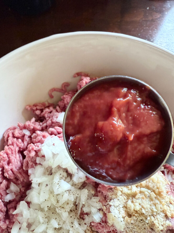 Adding some of the tomato sauce to the meatloaf mixture.