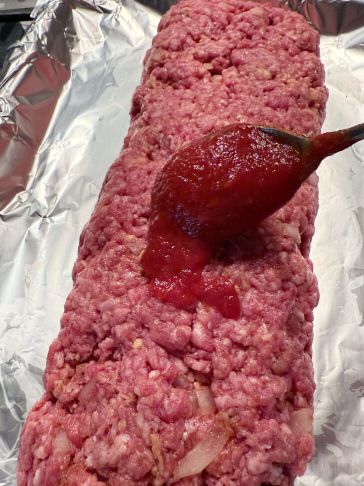 Spooning the remaining tomato sauce onto the meatloaf.