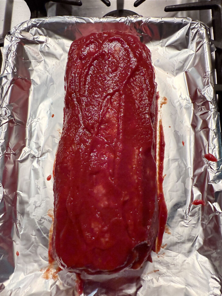 Meatloaf after being coated in the tomato sauce.