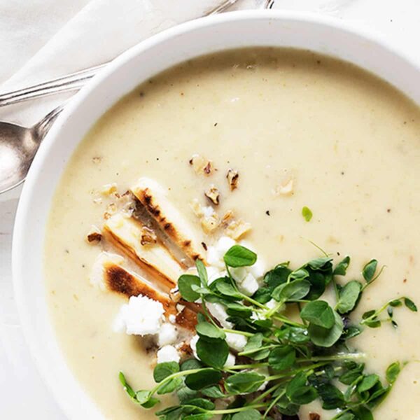 parsnip and pear soup in white bowl with garnishes on top