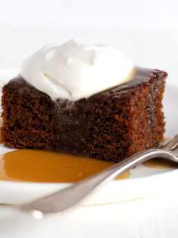 gingerbread cake on plate with caramel sauce and whipped cream