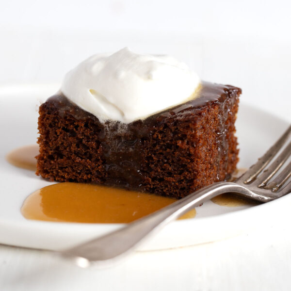 gingerbread cake on plate with caramel sauce and whipped cream