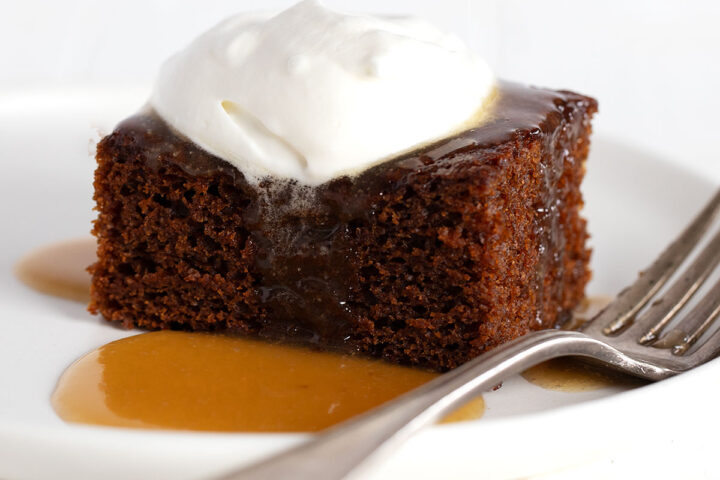 gingerbread cake on plate with caramel sauce and whipped cream