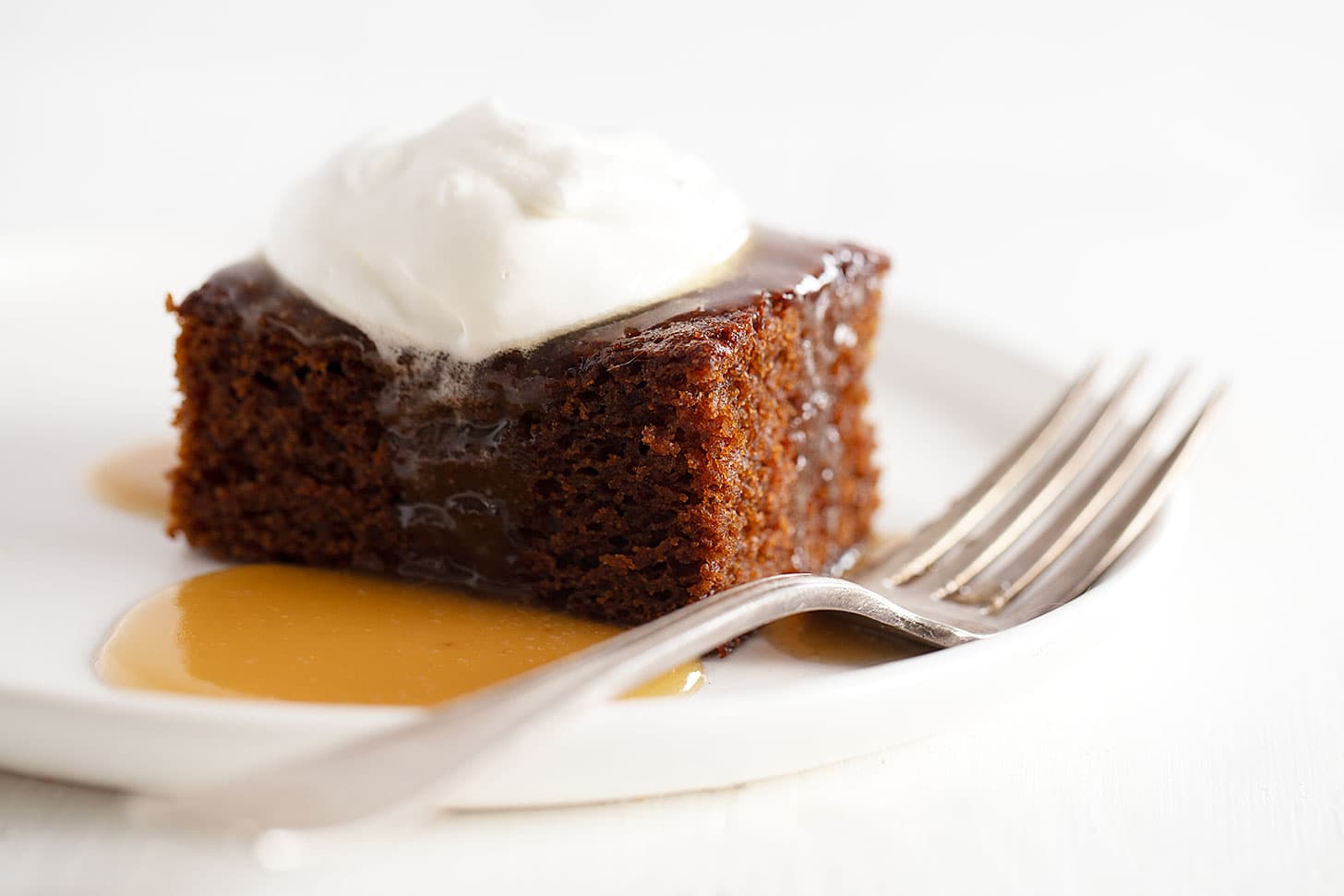 gingerbread cake on plate with caramel sauce and whipped cream