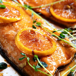 salmon on sheet pan with oranges on top