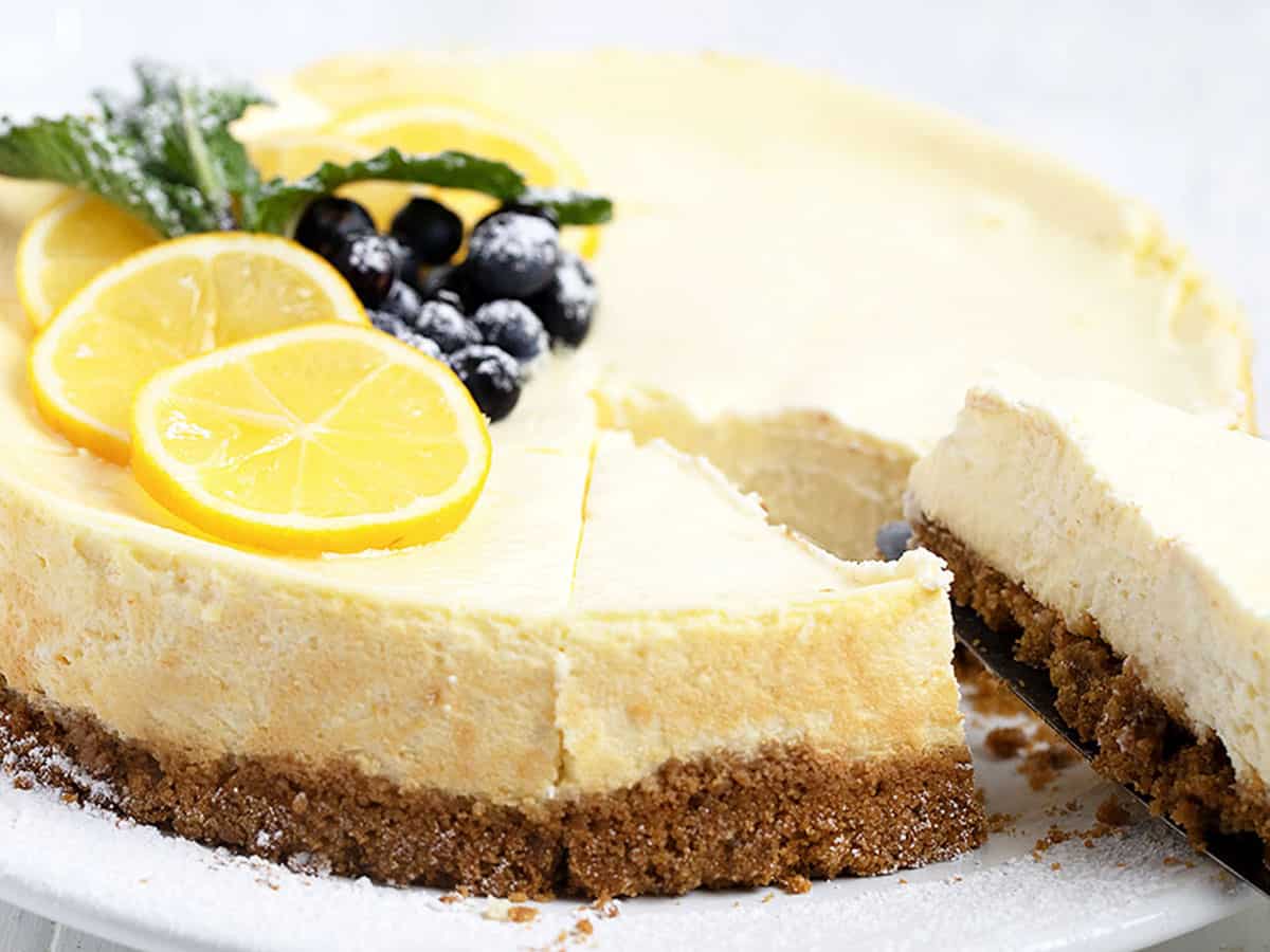 lemon cheesecake cut on plate with berries and lemon slices on top