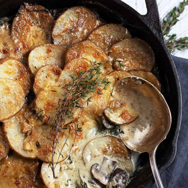 creamy potatoes and mushrooms in cast iron skillet with spoon