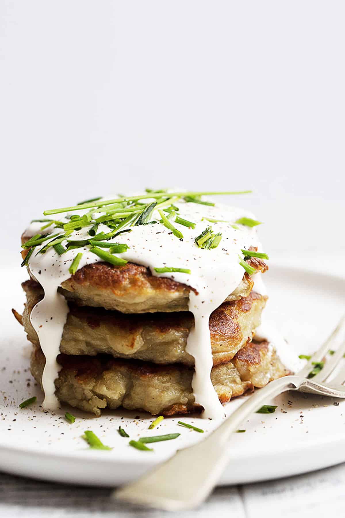 boxty stacked on a white plate with sour cream on top