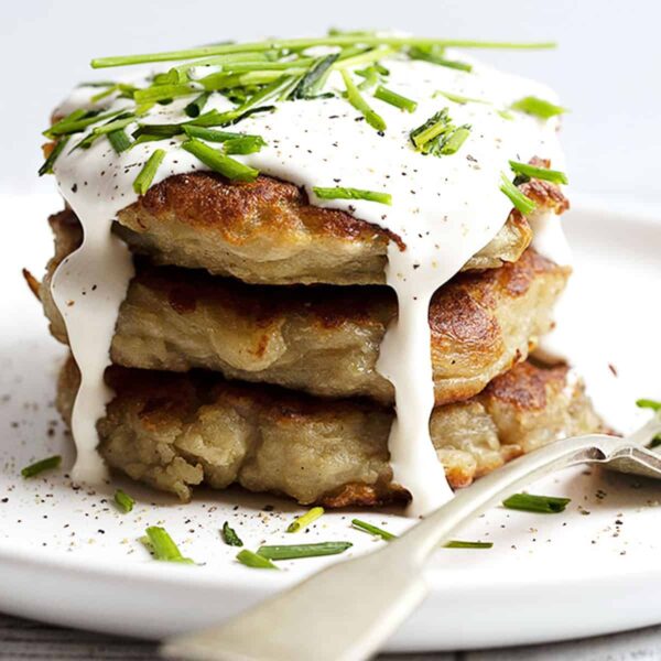 boxty stacked on a white plate with sour cream on top