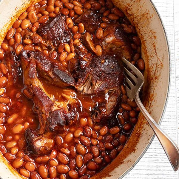 slow cooked pork and beans in casserole dish with spoon